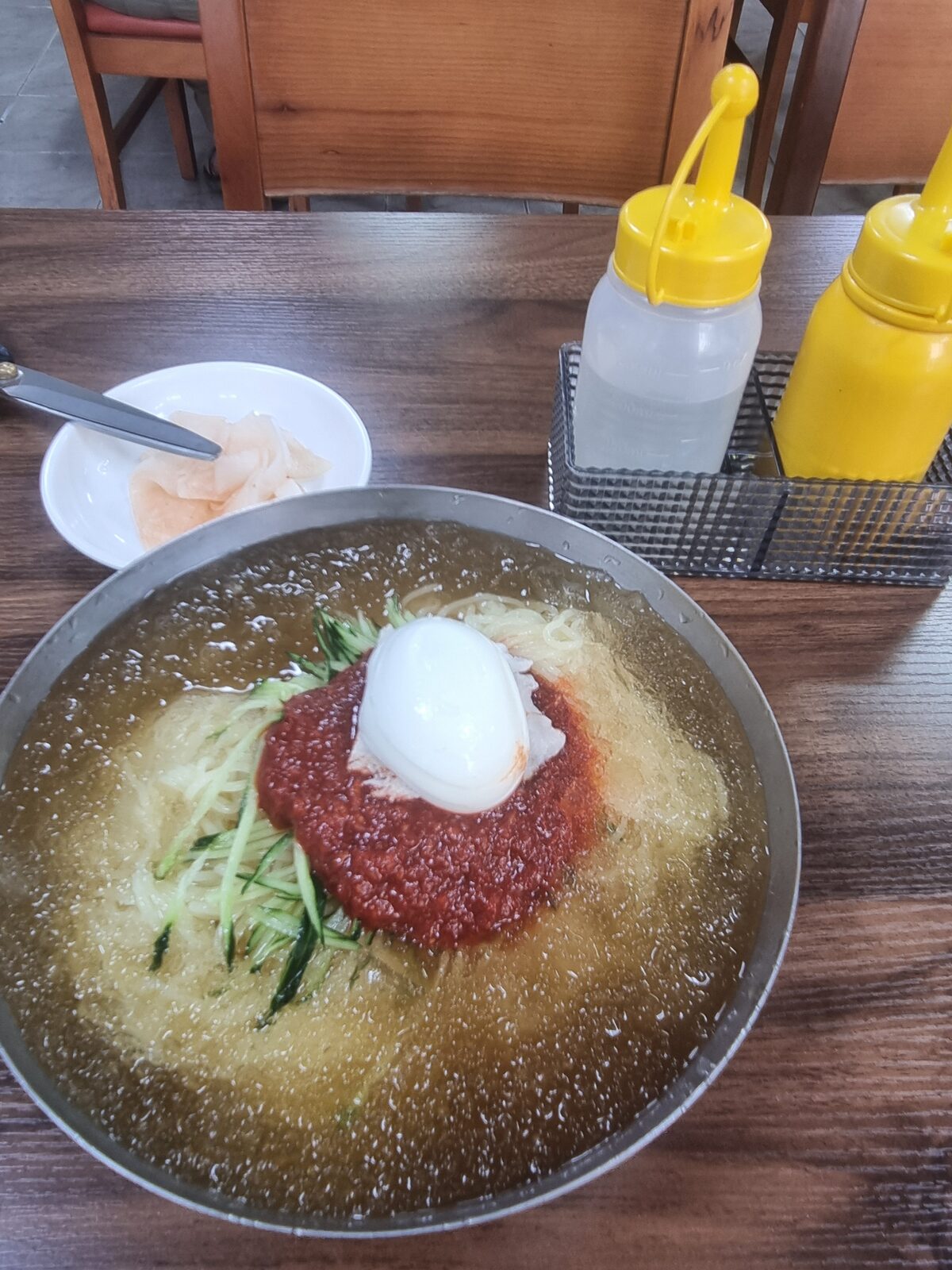 Busan mul-milmyeon cold wheat noodles in iced broth with red dadaegi paste on top