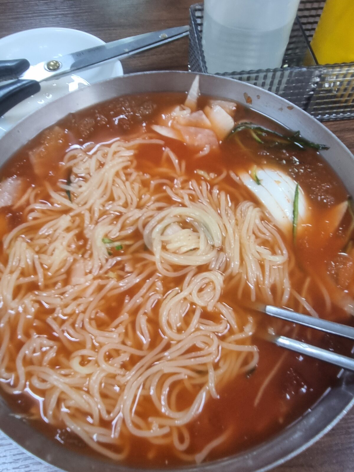 Milmyeon after stirring in the dadaegi paste, broth turned red, scissors on the table
