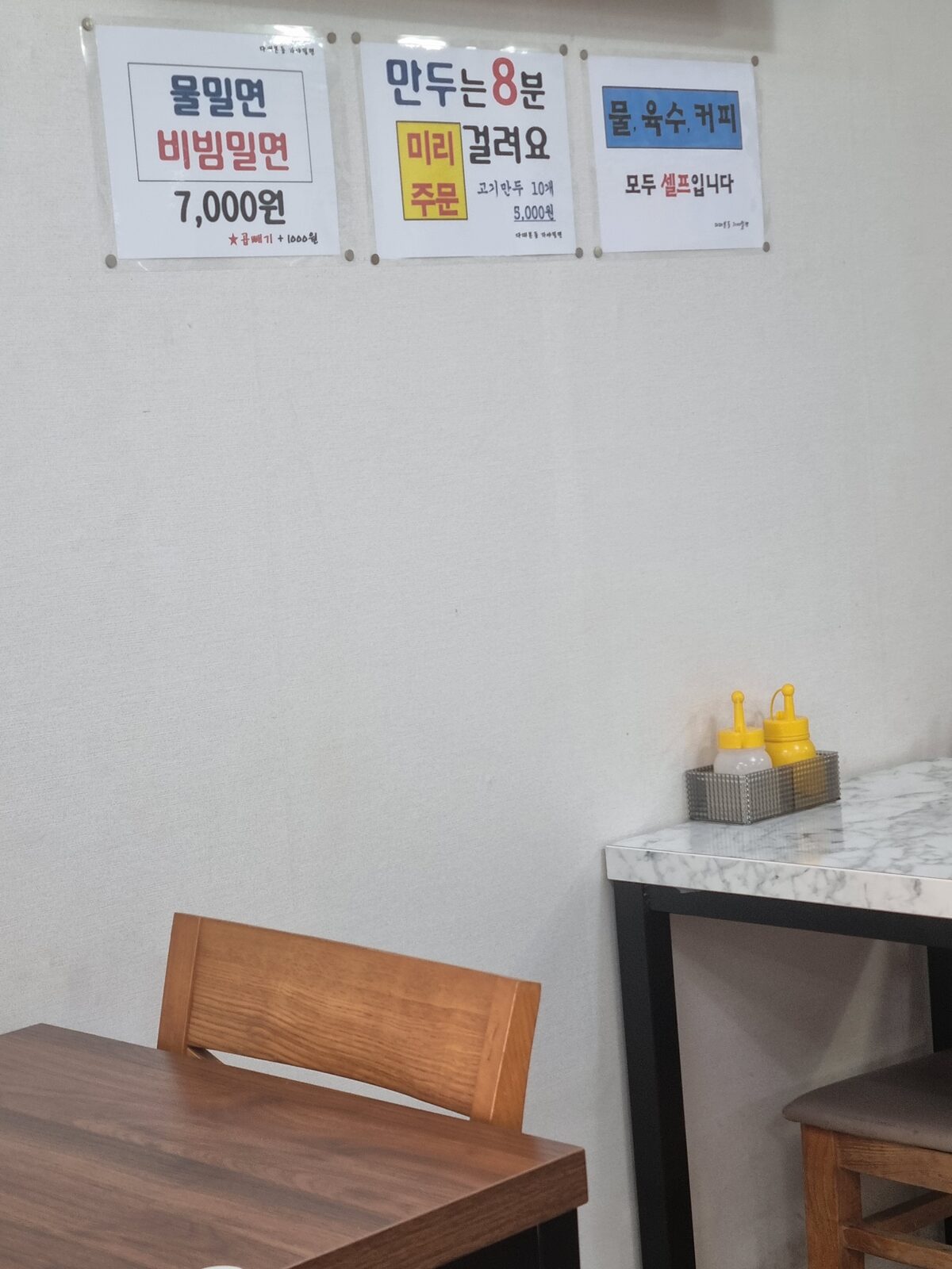 Wall notices at a Busan milmyeon shop: 7000 won, extra noodles 1000 won, water and broth self-service