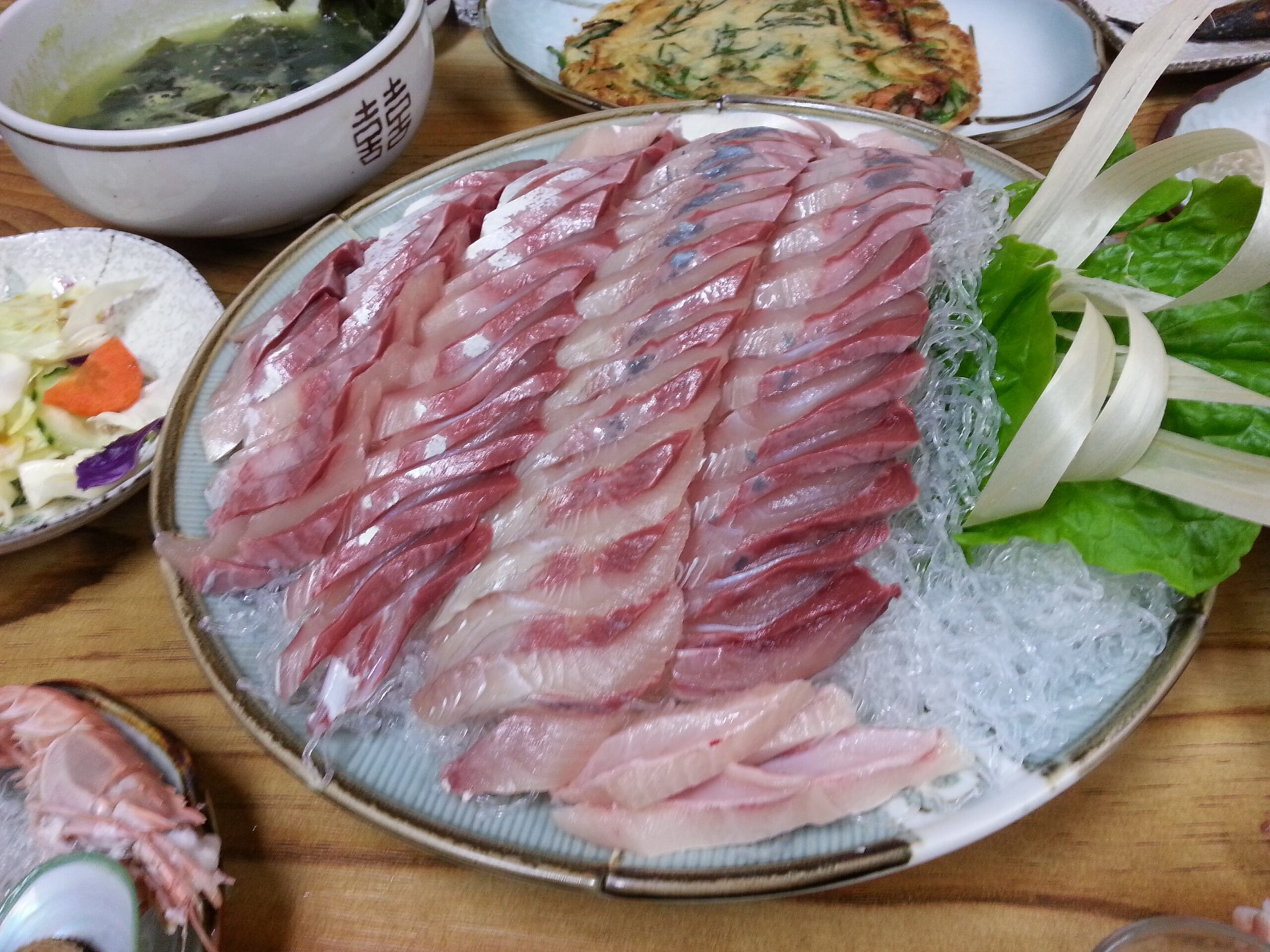 Thick slices of pale pink yellowtail sashimi fanned over ice