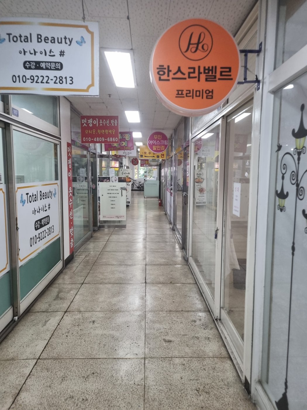 A quiet indoor arcade corridor lined with small glass-fronted shops