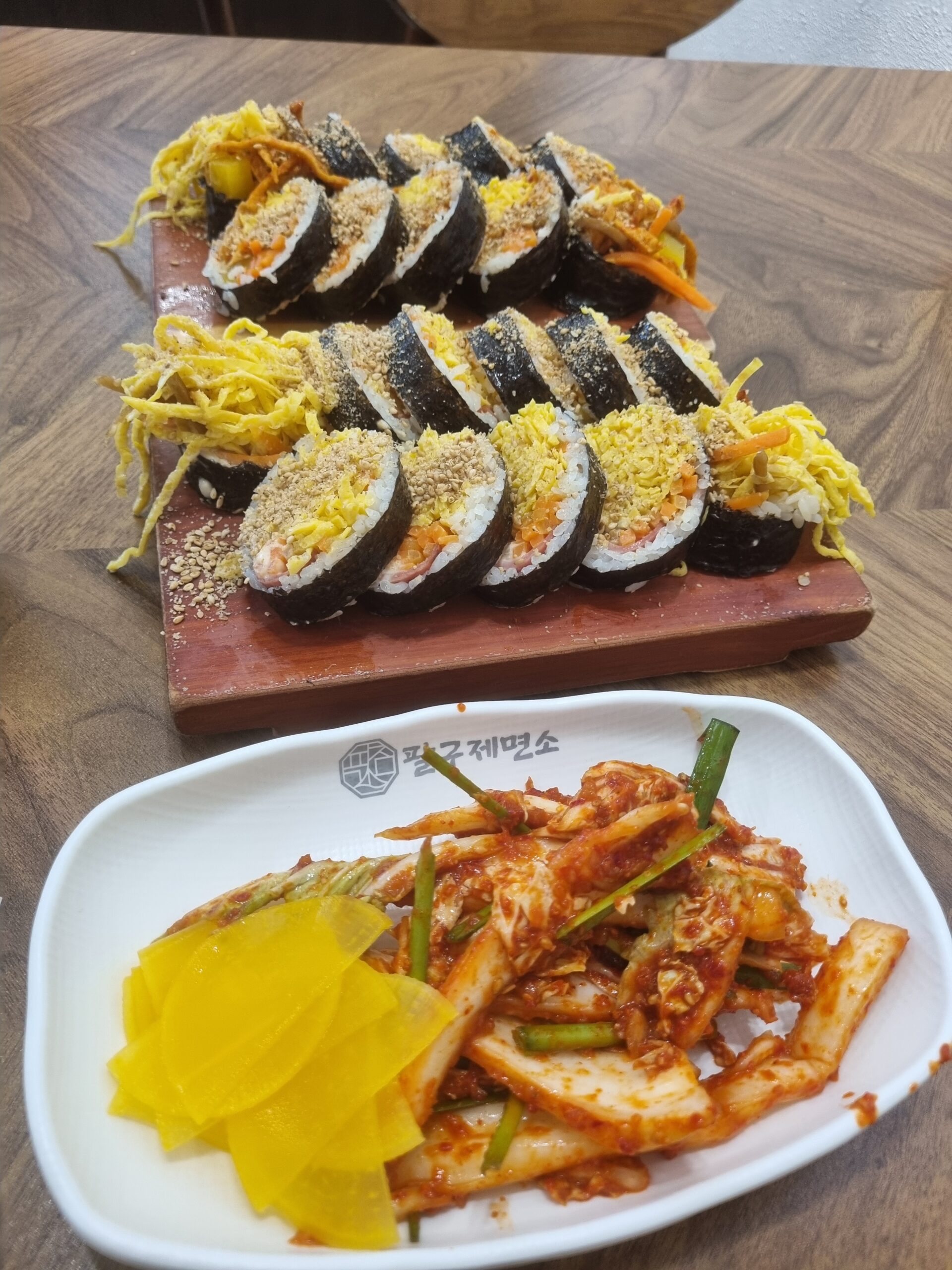 Close-up of gimbap cut faces showing shredded egg, carrot, ham and rice under a sesame seed coating
