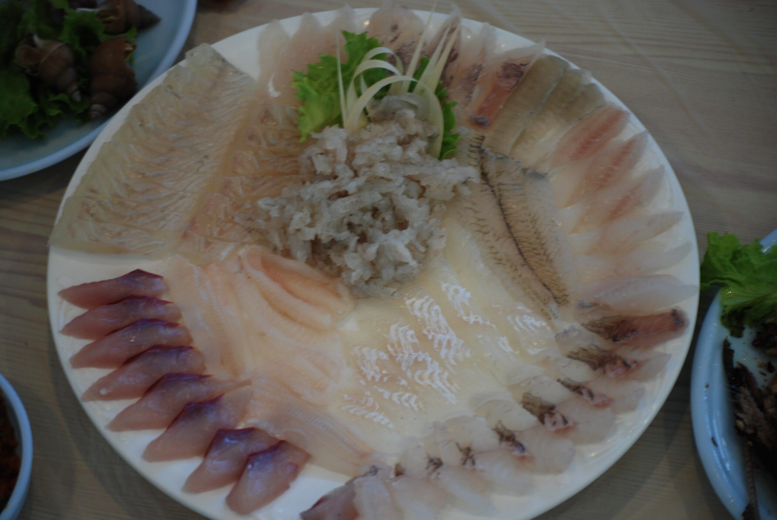An assorted modeum-hoe platter with several species of raw fish arranged around a central mound