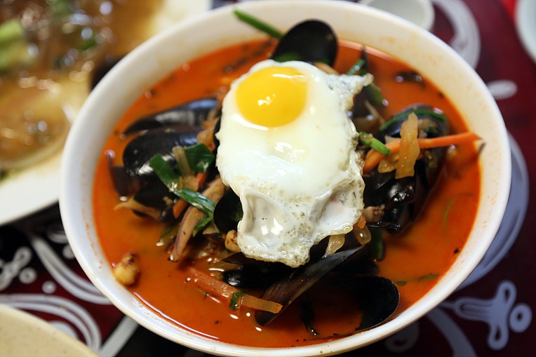 A bowl of red spicy seafood noodle soup