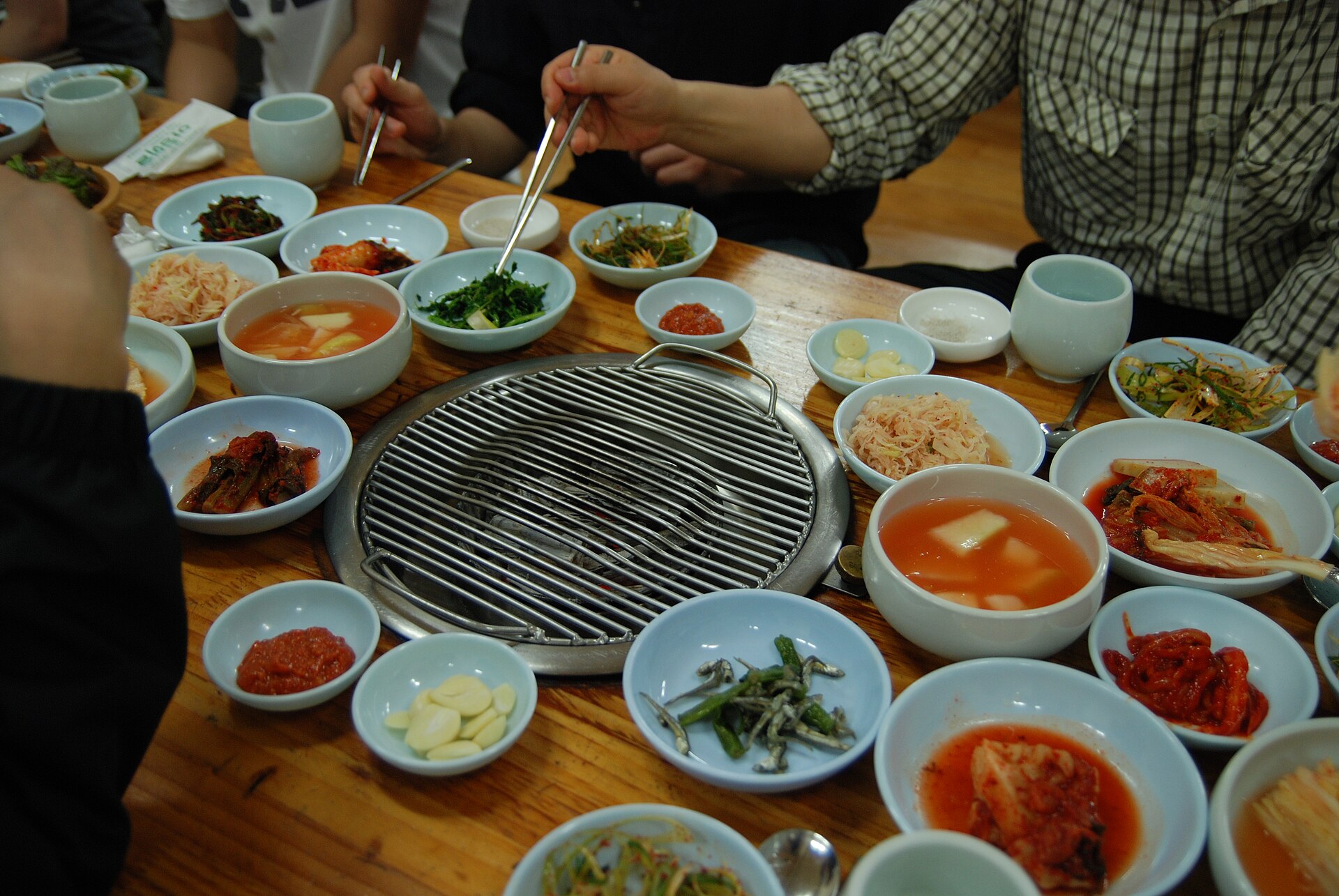 A Korean barbecue grill set into the table, surrounded by small side dishes