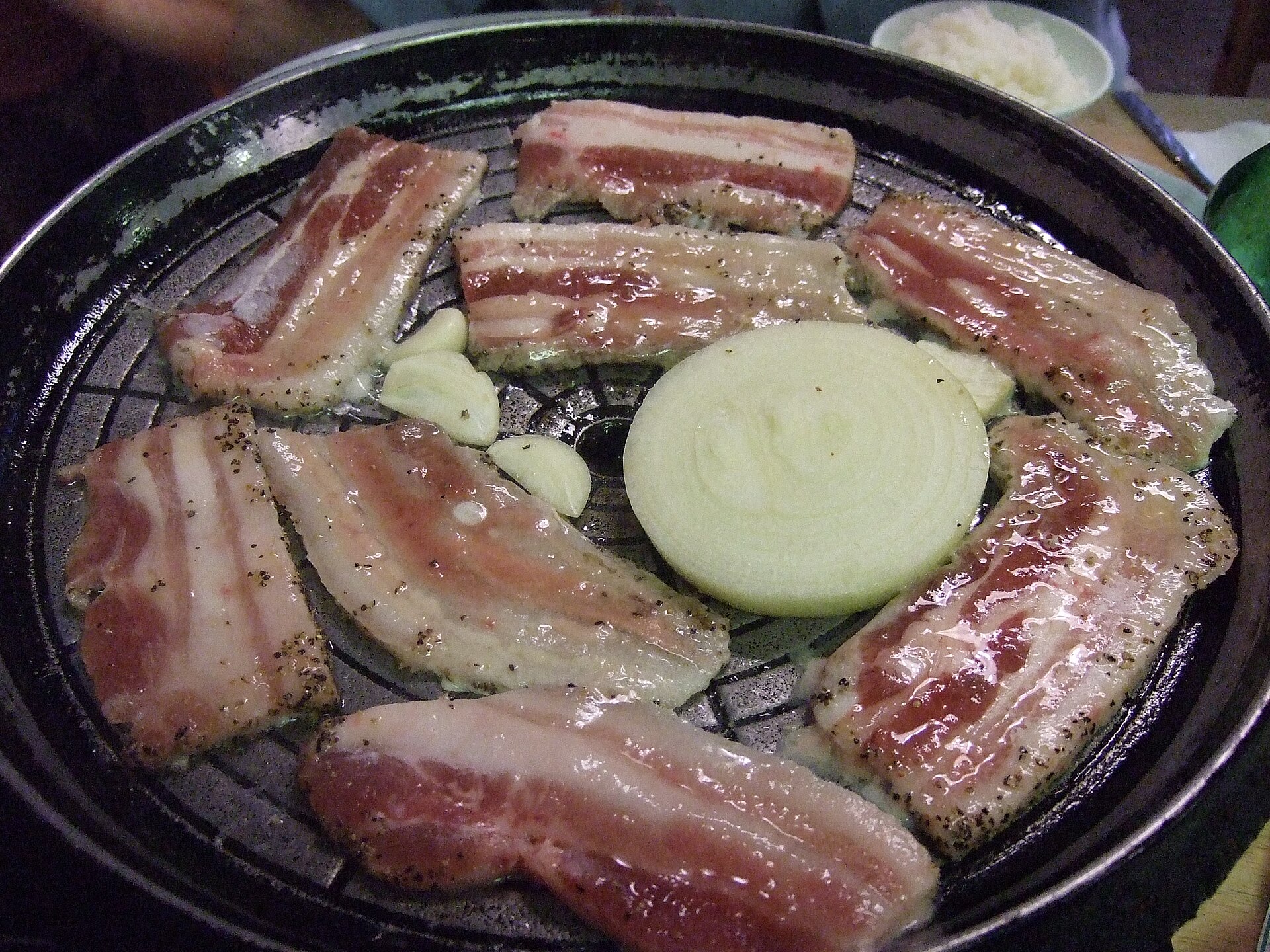 Pork belly cooking on a tabletop grill