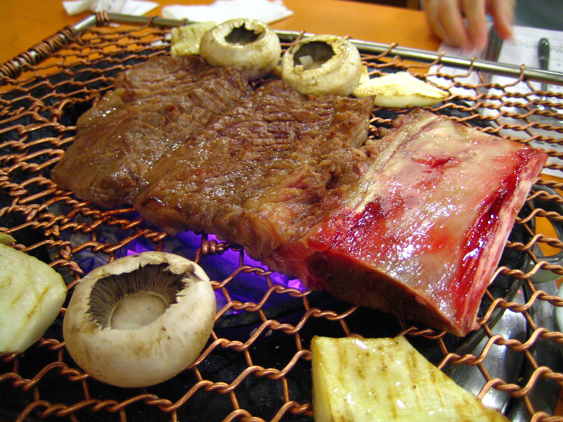 Marinated beef short ribs grilling over a fire